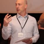 Michael, CEO of Consulting Succcess presents complete consulting marketing strategy guide to a room of consultants.