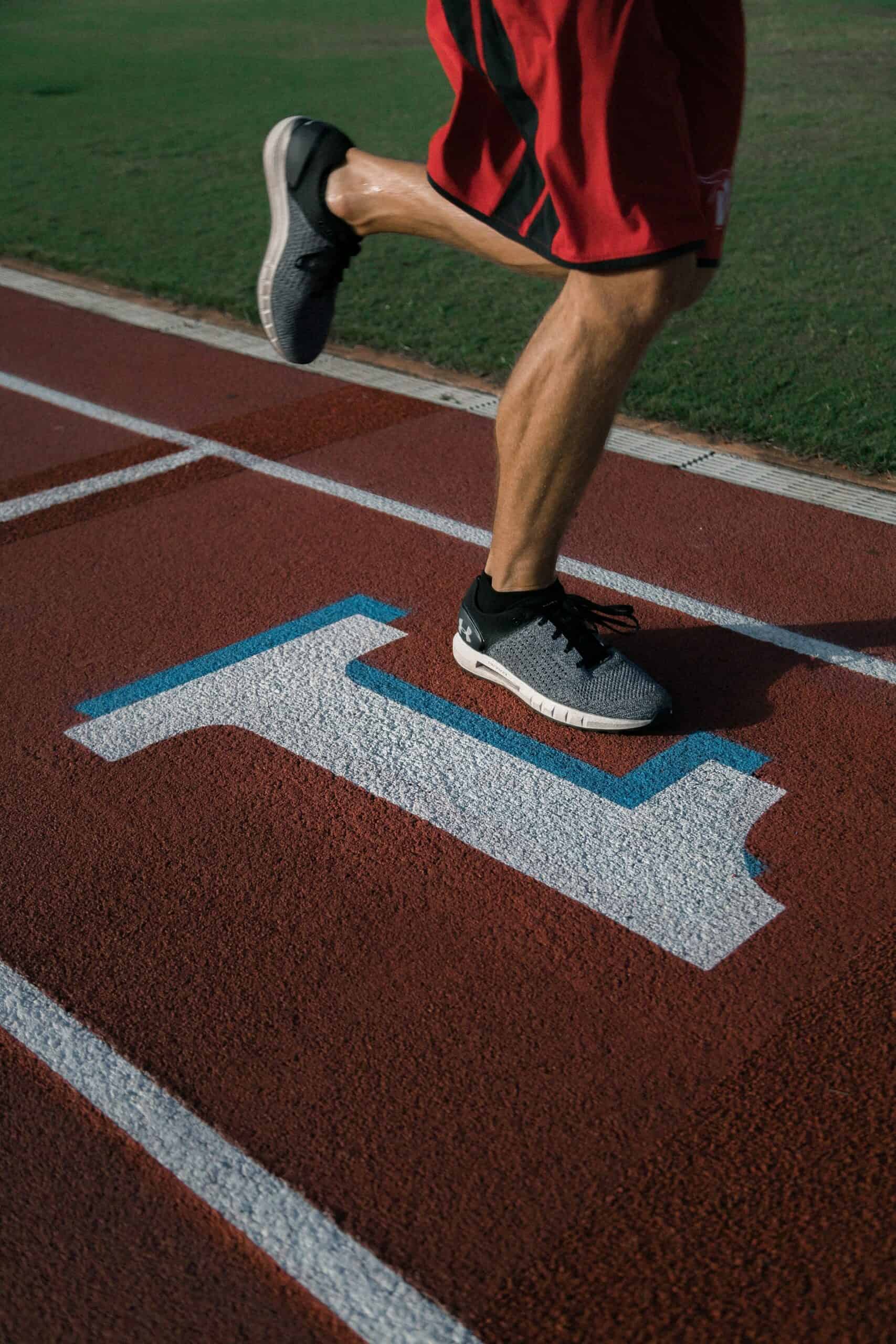 Runner's feet mid-stride on a track lane marked with a #1 symbol, representing the pursuit of being first place.