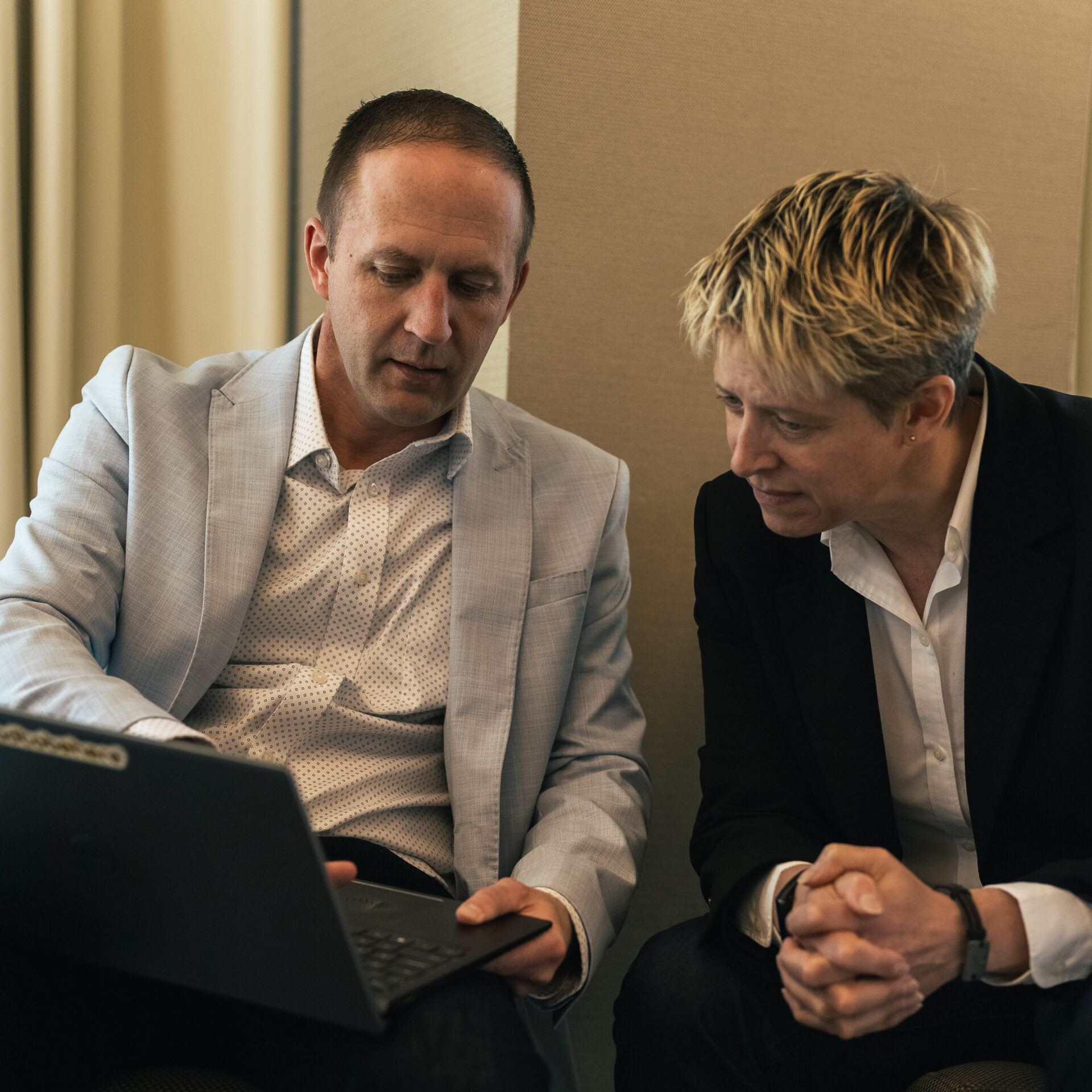 A consultant walking a client through a proposal on a laptop during a calm value conversation about an expanded scope and fee.
