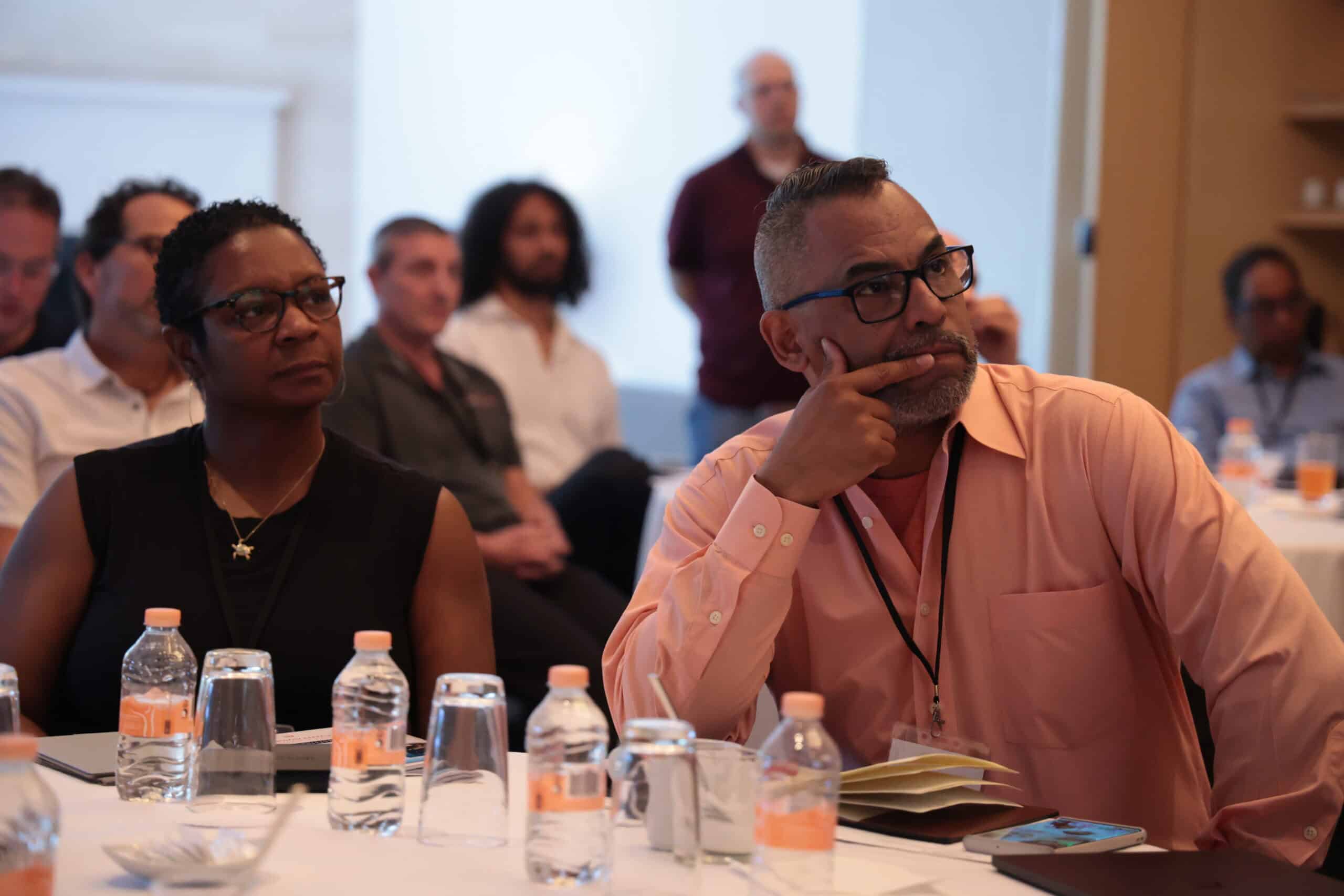 Established consulting founders listening intently during a session at a Consulting Success mastermind retreat, one resting his chin on his hand in thought.